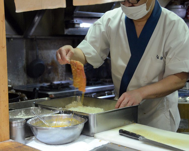 たっぷりの卵に肉をくぐらせた後、パン粉の中へ。このパン粉もあのサクサクの食感の源に。
