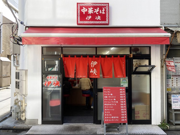 『伊峡』の目印は、赤いのれんと看板だ。一目でわかるラーメンの値段に惹かれて入店する客も少なくない。