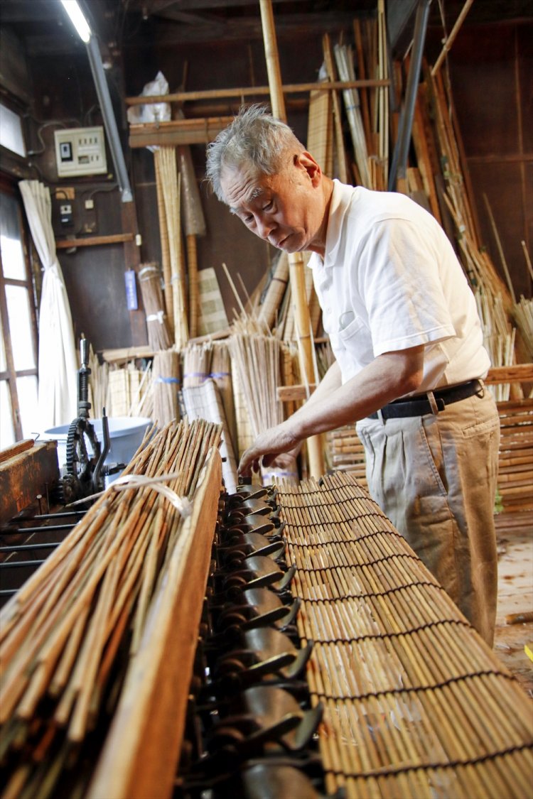 古風な編み機に一本一本葦を入れて足踏みで編む。