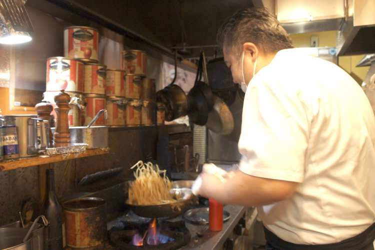 豪快にパスタをあおる、2代目店主の上野義巳さん。