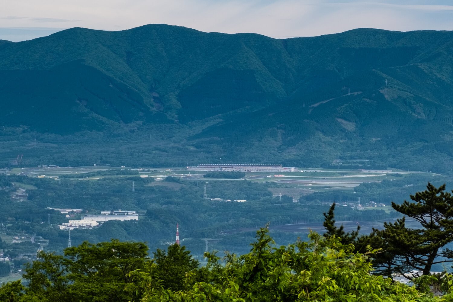 足柄峠からトレイルを遠望。稜線手前には日本で初めてF1GPが開催された富士スピードウェイが見える。