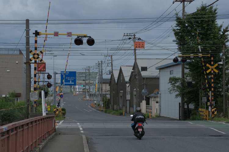 高島貨物線の踏切から瑞穂埠頭を望む。薄緑色は道路橋の瑞穂大橋。青い標識に隠れているが瑞穂橋もある。