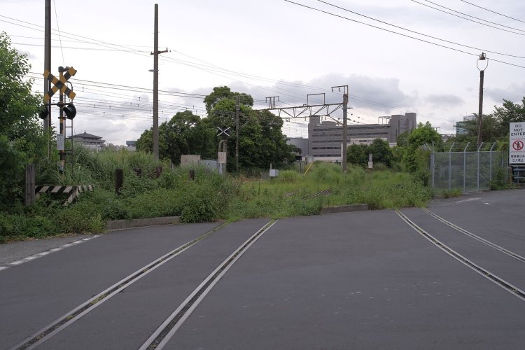 「塩業」と表記された踏切。奥が高島貨物線。複線分の線路がある。
