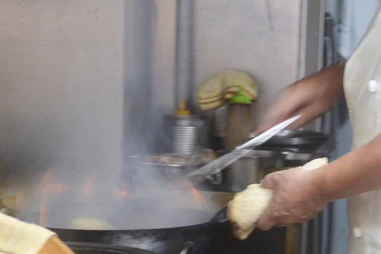 2代目御主人の華麗な鍋捌きで大量のナスがあっという間に炒められていく！