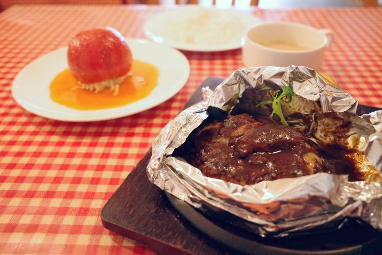 平日ランチのあいだハンバーグ（単品）は1500円、土・日・祝は1400円。＋200円でライスとスープのセットにできる。トマトのファルシーサラダ（左奥）は550円。