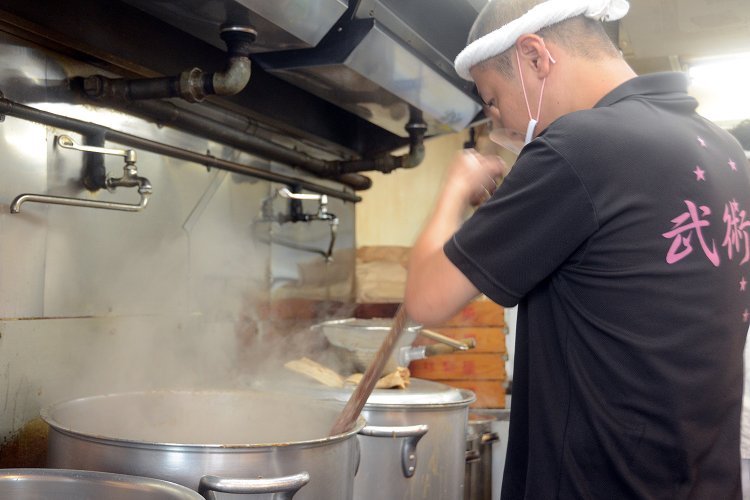 スープを作る寸胴は営業時間中も煮詰められた状態。そのため、常にスタッフが寸胴をかき回す。オールのような器具でかき混ぜるというかなりの重労働だ。
