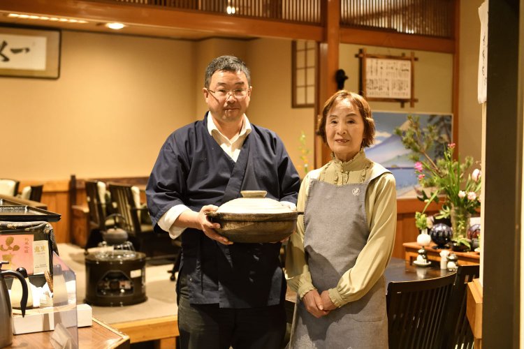 白米を炊くときに使う土鍋を手にする飯塚さんと、サービス担当のお母様・節子さん。お父様の一佳さんも一緒にカウンターに立つという。