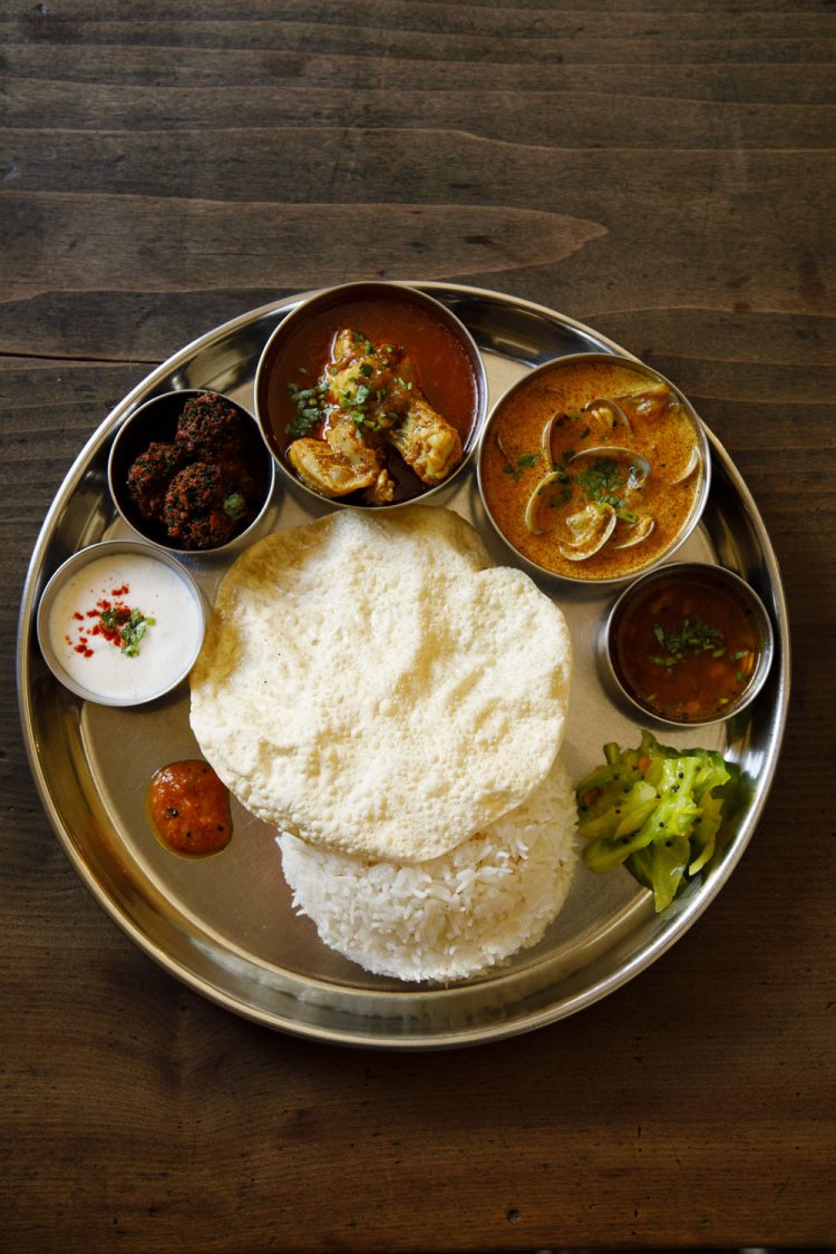 日替わりカレー1300円～。この日はあさりココナッツとチキンカレーだ。胡椒の辛さとタマリンドの酸味が後引くラッサムや、野菜の揚げ物やアチャールも付いて豪勢。