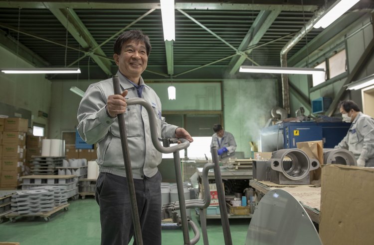 吉川さん。手に持つのは観光バスのドア戸閉装置だ。