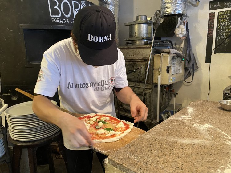 ソースやチーズ、トッピングを乗せたピッツァを窯へ入れるのにも熟練の技が求められる。