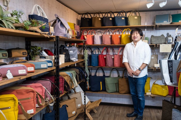 郊外にある縫製工場を兼ねた店舗で帆布製品に囲まれる小曽戸聡さん。