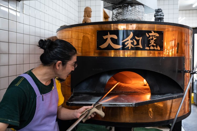 日本橋の『山宮かまど工業所』製特注薪窯と店主の井上俊輔さん。