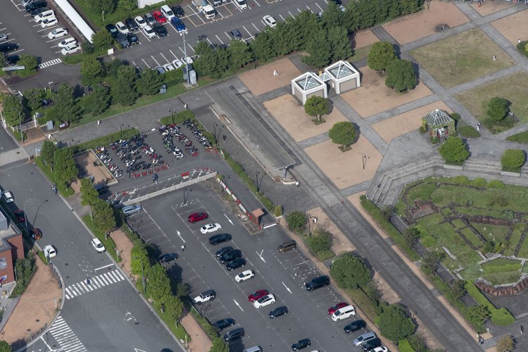 上から見ているので地面と同系色になって擬態化しかけているが駐輪場右横に短いプラットホームとT字状のホーム屋根が見える。保存された横浜港駅の一部分である。線路も分かる。