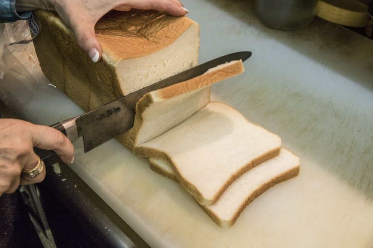 マスターが卵を焼き始めると同時に奥さんがパンをカッ ト。