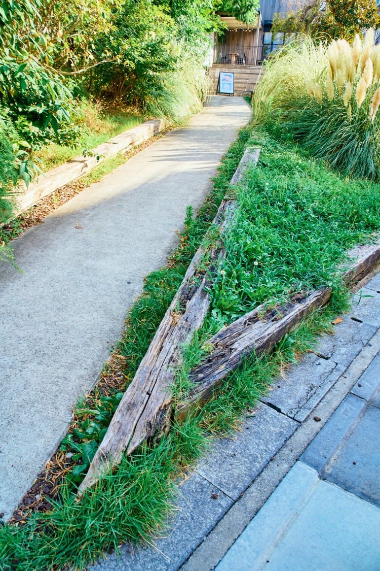東横線で使用された枕木を土留めや看板に活用。ナチュラルガーデンのよう。