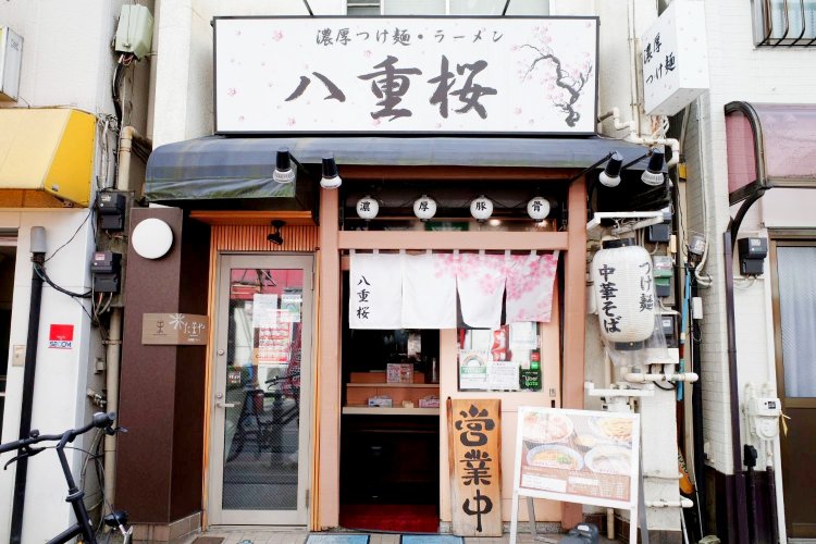 王子のシンボル的レトロマンションである飛鳥山スカイハイツを囲むように小さな店が並ぶなか、目に入る八重桜の看板。