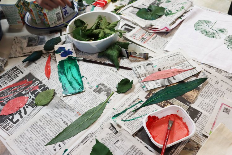 この日もボランティアさんたちが、ワークショップに使うティーマットに、アクリル絵の具を塗った葉で模様をつけていた。