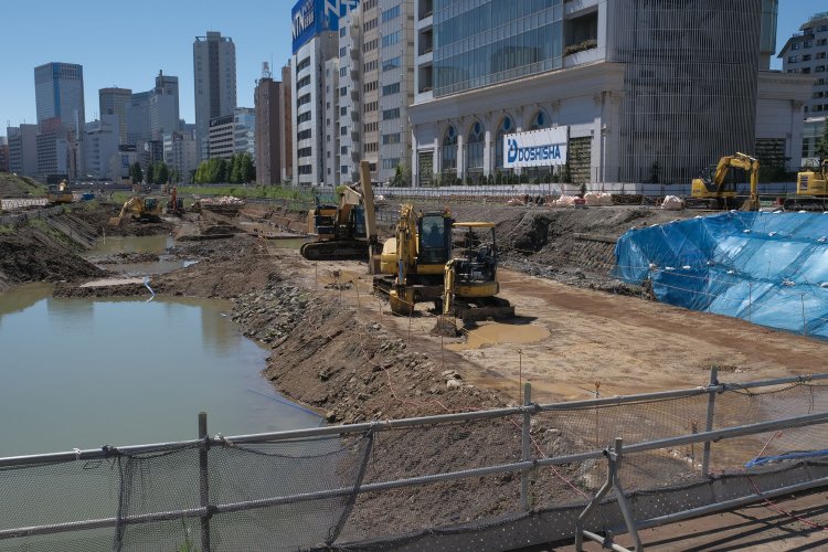 見学ルートから。重機のある位置が築堤。石垣も撤去されているが、辛うじて築堤だと分かる。前日の大雨で水が張っていた。左が海側の石垣部分にあたる。重機背後に海岸線の敷地境界擁壁もみえる。