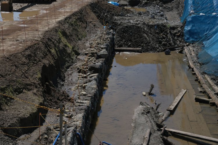 上記写真の右側を拡大。開業時の築堤の石垣部分（写真中）、３線化へ増幅時の石垣部分と、水溜りに沈む胴木の板張り（写真右）。