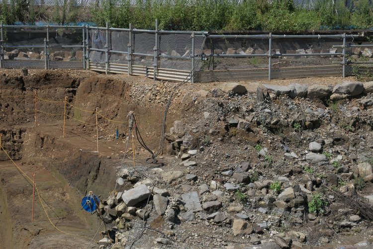 柵の下部分の小石は線路敷きに使用されたバラスト。開業時の頃のものらしい。手前でゴツゴツしている石は裏込石だ。