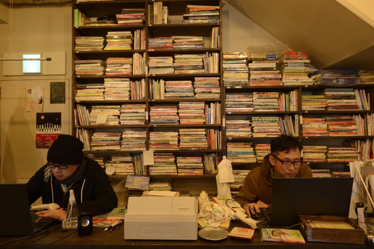 レジカウンターの背にもまるで地層みたいに本が山積み。