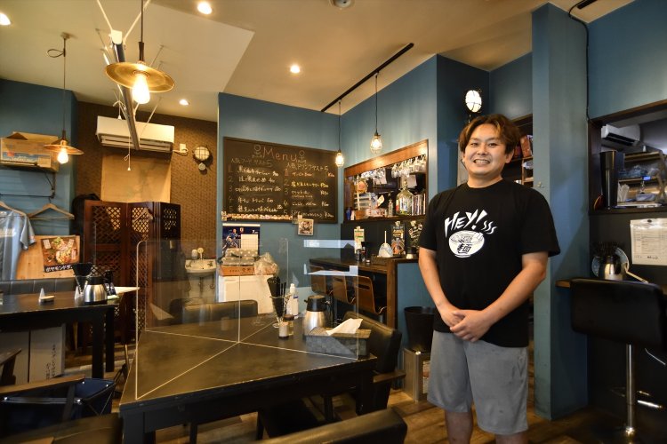 貝原さん。海をイメージしたブルーの壁が映える。