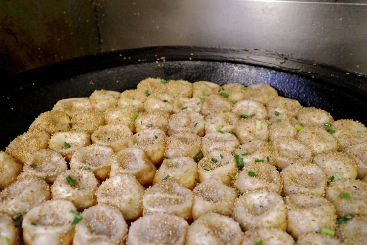 店頭の特製大鍋に小籠包を並べ、皮の底は揚げ焼きにする。その後、水をかけて蓋をしてから焼きあげていく。できあがりまで7～8分。焼くたびに売れていく。