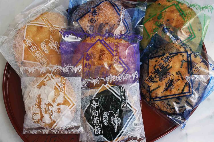 人気の煎餅。上から時計周りに「ざら丸」、「ごま」、「満月」、「のり丸」、「白雪」、「かたやき」、中央は「あつやき」１枚各70円。