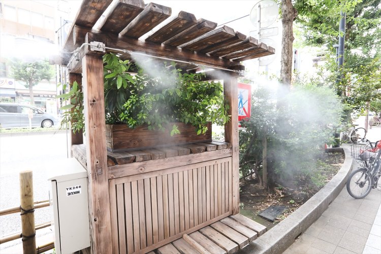 ミスト噴射の緑の屋台が植え升内に。『三省堂書店』前に置かれたヒートアイランド対策を掲げるベンチ。