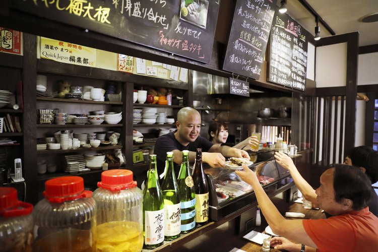 カウンター越しに料理を出す松井さん。