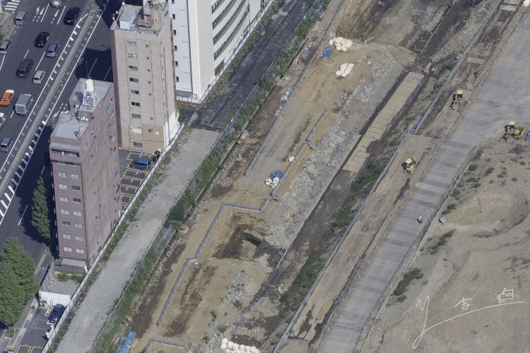 高輪ゲートウェイ駅前の築堤部分。信号機土台は青色の土嚢が置かれている近辺にある。信号機土台30m部分が移築保存される。2021年10月6日撮影。