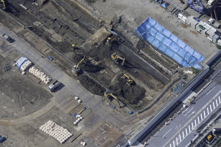 見学会で初めに見学した箇所を上から見る。ビニールシートがかかる部分が海岸線。敷き詰められた板は３線化の石垣土台の胴木である。2021年10月6日撮影。