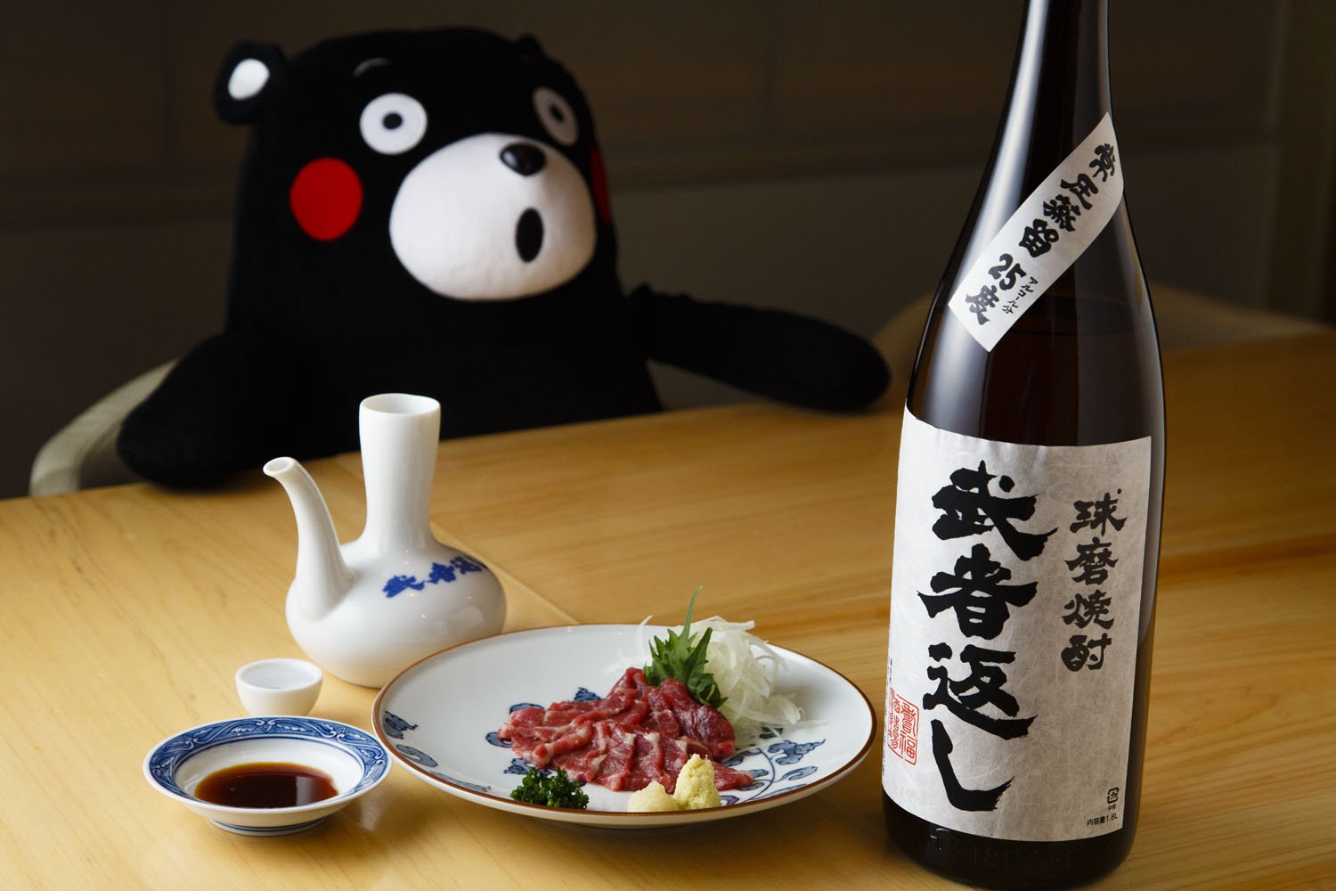 焼酎は酒器に入れてお猪口で飲むという熊本の伝統スタイル。熊本直送の馬刺し900円。店のマスコットのくまモンは常連客からのプレゼント。