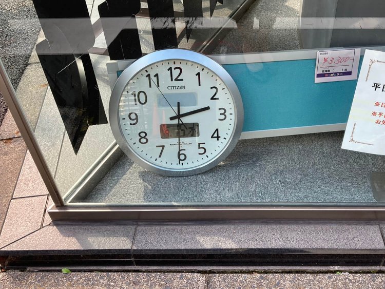 神田の店舗にある時計。外に向けられているからには通行者向けなのだろうが、なぜ床に置かれているのだろう。