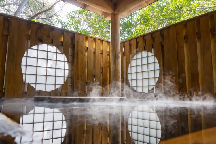 高見風呂は、浴槽を木で囲んだ落ち着いた空間。格子をはめた丸窓が和の情緒を醸し出す。