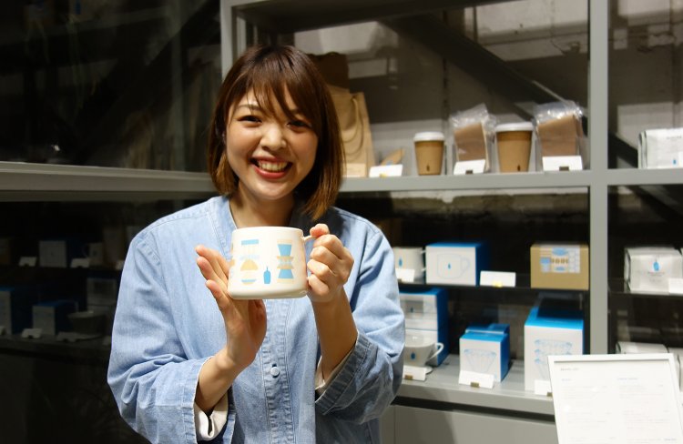 店長・鈴木理恵さん。店舗でもコーヒー豆やカップなどコーヒーグッズの購入が可能。鈴木さんのおすすめは、コーディー・ハドソンがデザインした数量限定のホリデー仕様の清澄マグ。