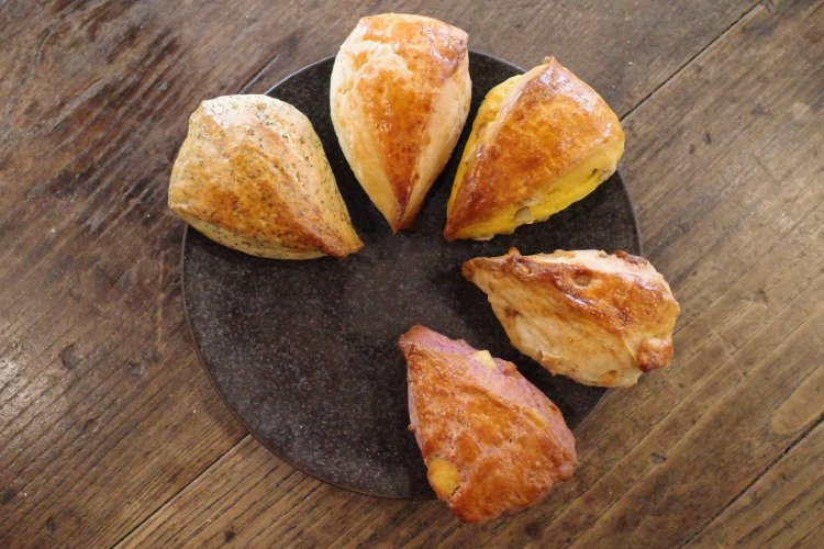 三角のスコーンはしっとりホロリ。左上から時計回りに、紅茶、プレーン、かぼちゃ、くるみといちじく、紫いもとホワイトチョコ。1つ300円。