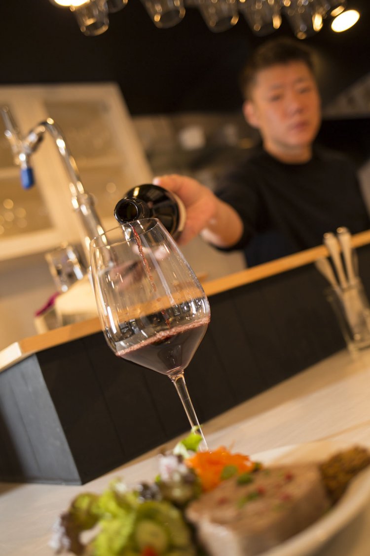 春山さんがカウンター越しに接客する。グラスは赤・白各4種、泡1種、各900円～。「もっと自由にワイン飲もう」。