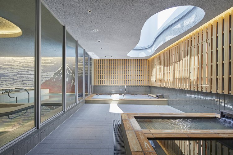 雲形に開いた天井から日差しが入る女性浴室露天風呂。