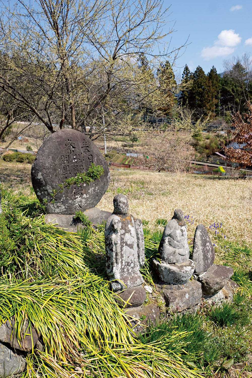 小倉集落の道端に出羽三山の石碑と顔が風化した石仏が佇んでいた。