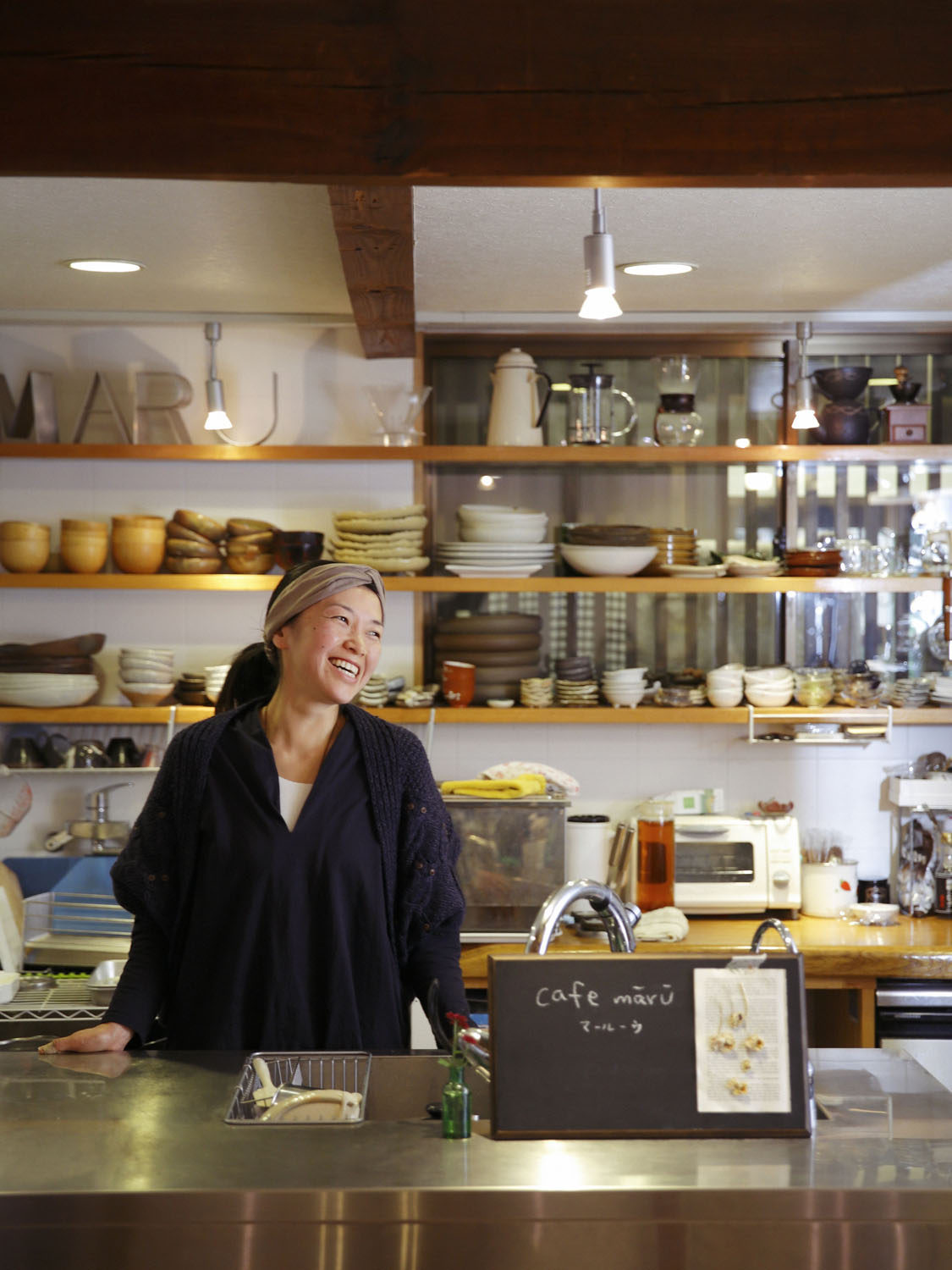 開放的なキッチンで照れくさそうに笑う店主の町田さん。