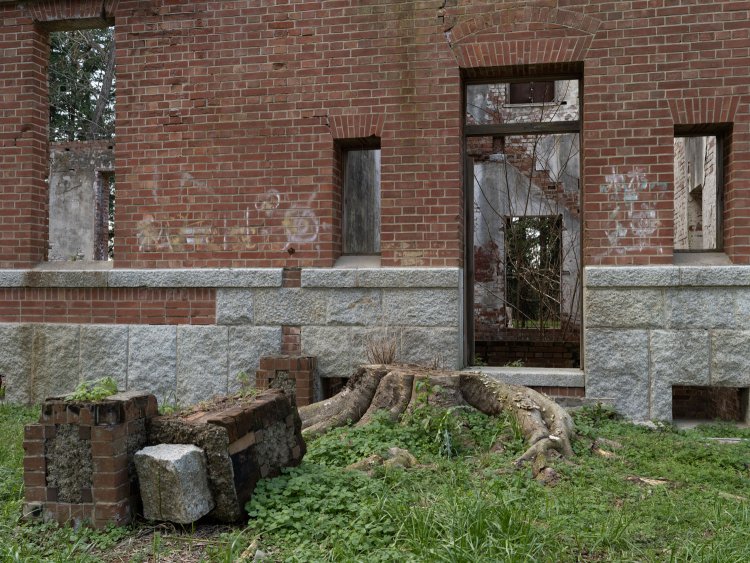 エントランス。白御影石の上にレンガを積んでいる。手前の門柱らしきものはバルコニーの土台かと思われる。空き家になった後は玄関に木が育ったが、保存整備時に伐採された。