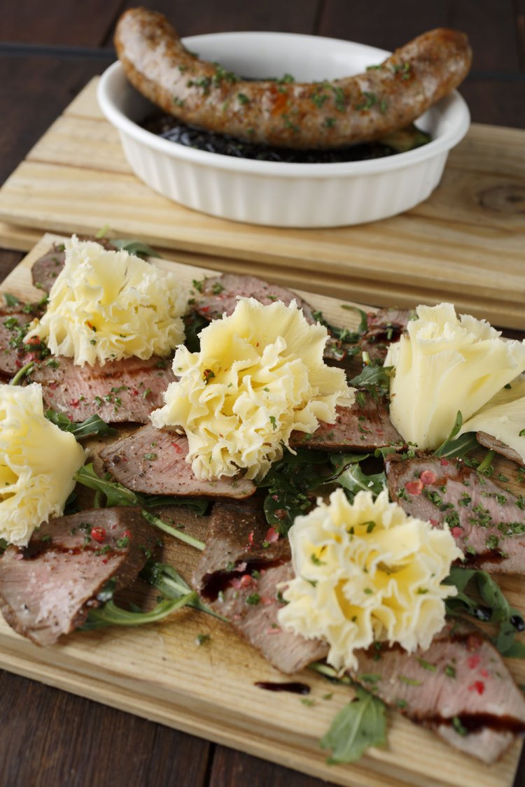 薄くスライスしたチーズをのせた、子羊のスモーク1566円。奥はラム肉の自家製ソーセージ＆レンズ豆の煮込み918円。