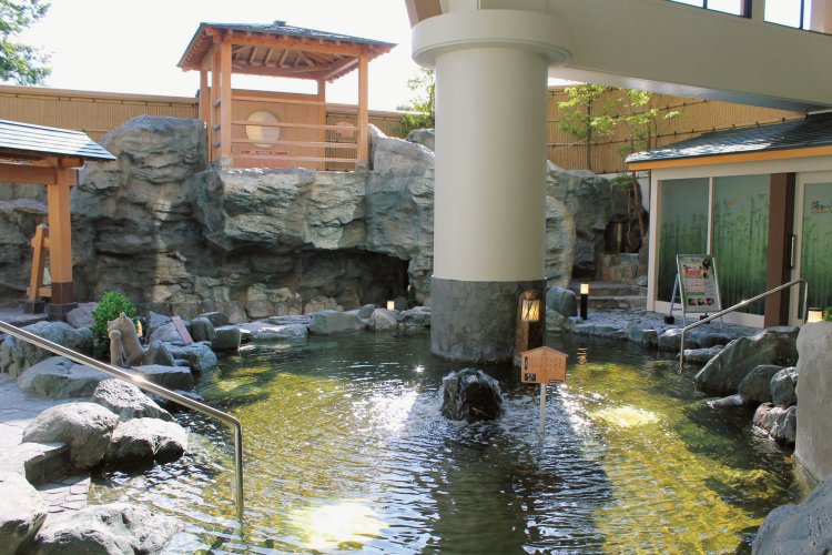 明るい日差しが心地よい風月の湯の露天風呂。おすすめの空中炭酸泉は岩の上にある。