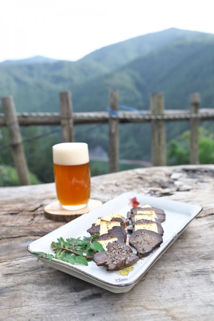 笹尾根を見ながら外で飲むこともできる。つまみはジビエの鹿の燻製とチーズ1350円。