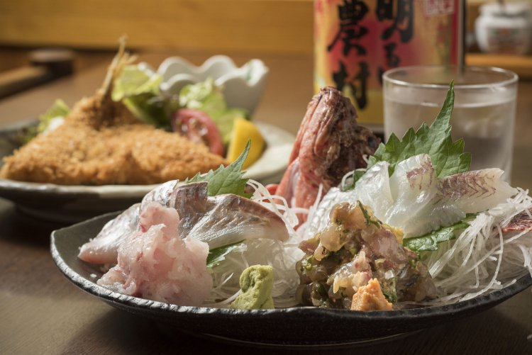 刺身盛り合せ（2名分）1731円と人気のアジフライ（特大）560円。明るい農村グラス540円は骨太の芋が香る。焼酎はデキャンタでのオーダーがお得。