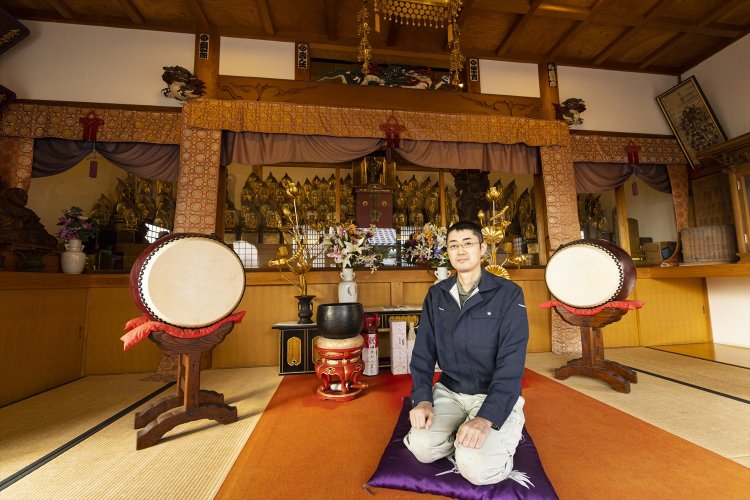 温泉の前に立つ百観音堂と、昌純さん。