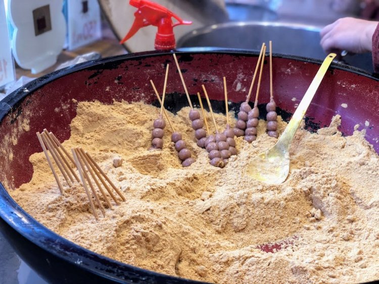 売り子さんが流れるような手つきできびだんごにきなこをまぶしてゆく。