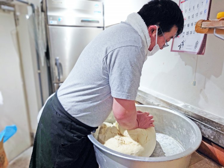 名物青竹手打ち麺。練り上げた麺塊を切り分け孟宗竹に足をかけ体重を乗せて伸ばしていく。