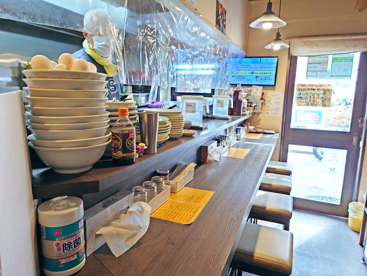 カウンター5席のこぢんまりとした店内。ダウンタウンや壇蜜さん、ディープな赤羽の街を描いた漫画家の清野とおる先生など、テレビで紹介された時の写真が飾られている。